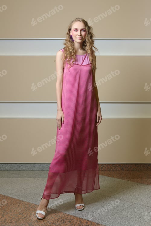 Preview: Cute happy girl with curly hair and in pink strap dress posing