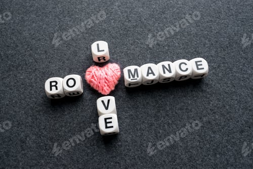 Preview: Love romance crossword block text with pink thread heart on dark felt background. Close up