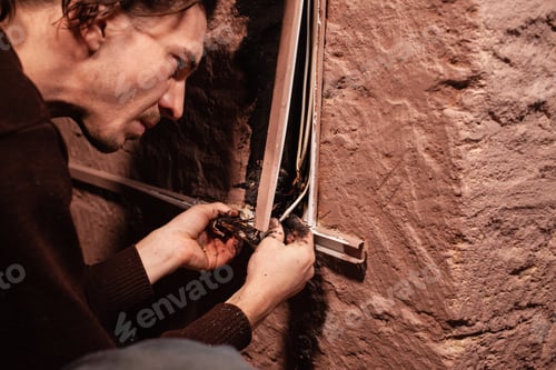 Preview: A man fixes a burnt socket. Short circuit, burnt wires. traces of smoke and fire on the wall. The