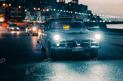 Preview: Vintage car driving down road in sunset