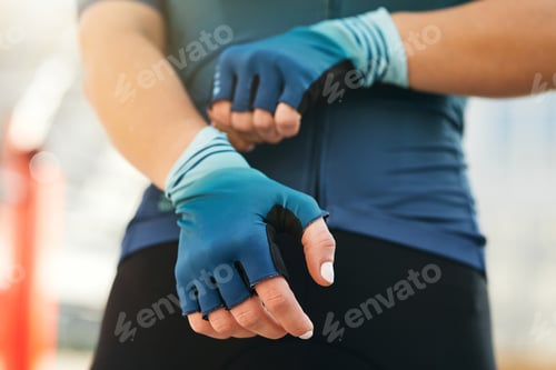 Preview: Professional female cyclist putting on cycling gloves while getting ready for training