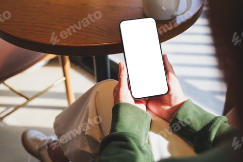 Preview: Mockup image of a woman holding mobile phone with blank desktop screen in cafe