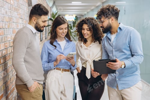 Preview: Business colleagues standing, sharing ideas, and discussing project details in a modern office