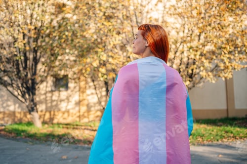 Preview: Young activist showing transgender pride flag in a park