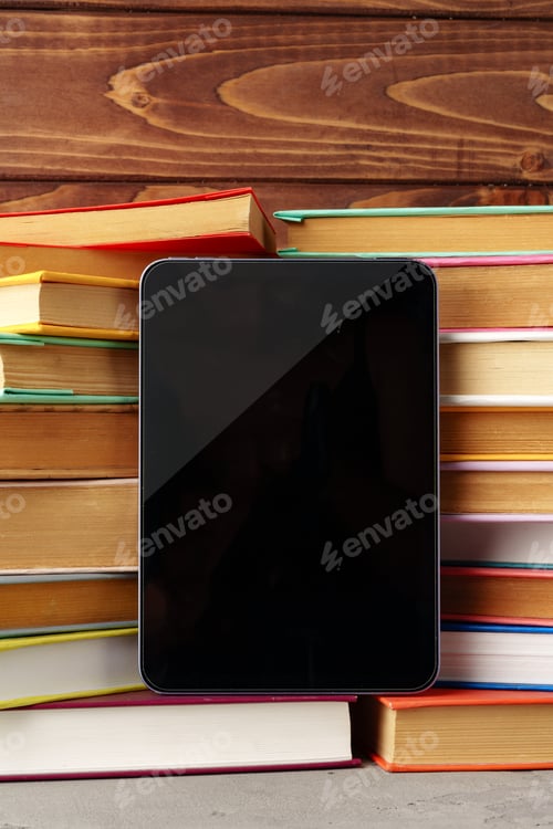 Preview: Digital tablet and stack of hardcover books against wooden background