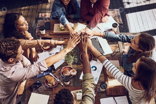 Preview: High angle shot of a group of creative workers high-fiving while out on a business lunch