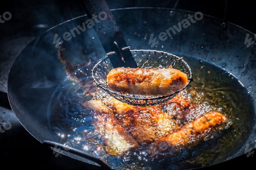 Preview: Homemade spring rolls frying in hot oil in black pan