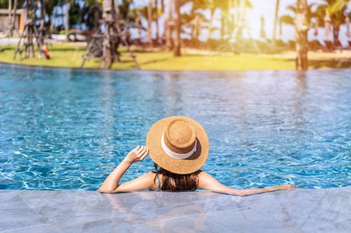 Preview: Young woman traveler relaxing and enjoying by a tropical resort pool