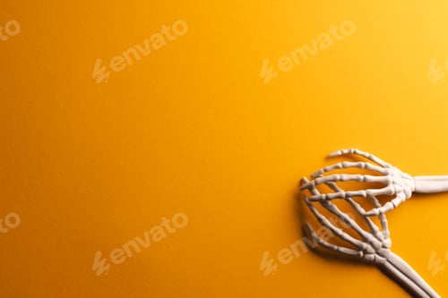 Preview: Plastic skeleton hands with copy space on yellow background