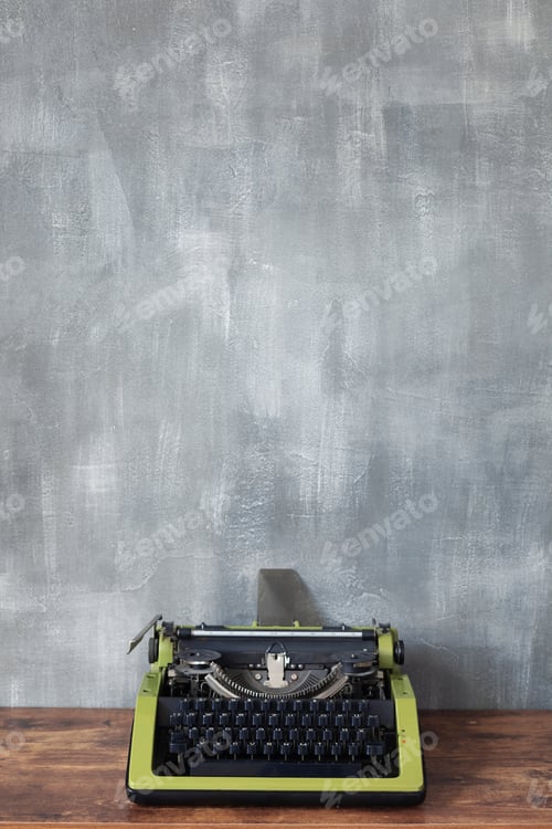 Preview: vintage typewriter at wooden table near wall background surface