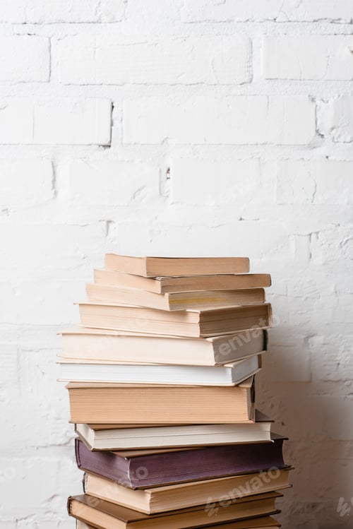 Preview: pile of books near white brick wall with copy space