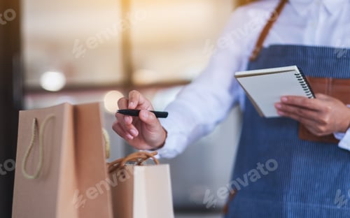 Preview: Closeup image of a female entrepreneur checking orders from customer