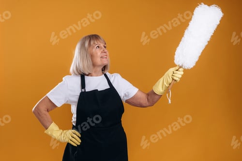 Preview: Ready to clean the house. Senior housewife is standing against background