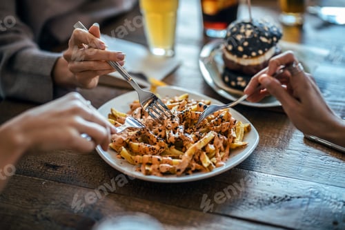 Preview: Hands of friends eating potatoes togheter while having fun in the restaurant.