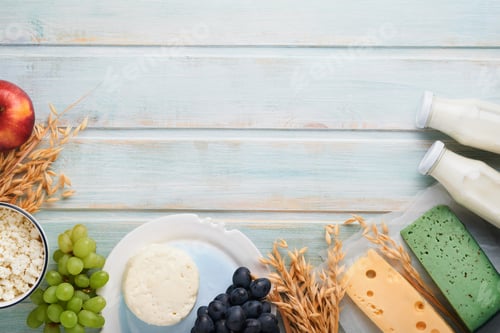 Preview: Shavuot jewish holiday celebration. Milk and cheese, ripe wheat and fruits, blue wooden background.