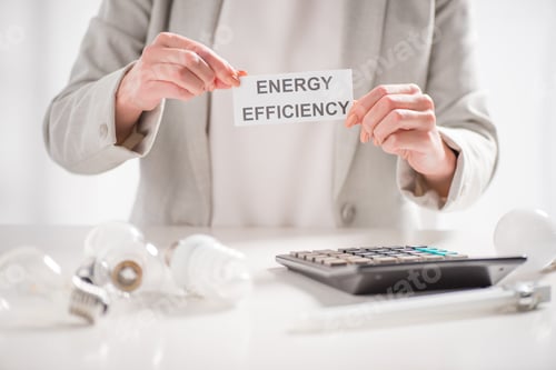 Preview: cropped view of woman holding paper card with lettering near lamps and calculator on white