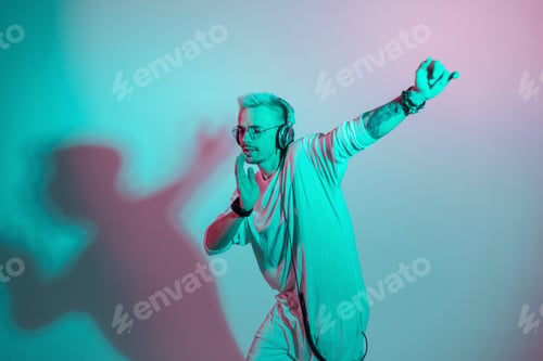 Preview: Handsome stylish dancer cool man in fashionable clothes dancing in colorful studio