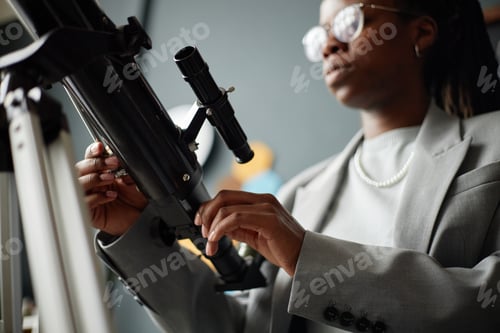 Preview: Young Adult Black Woman Adjusting Telescope Indoors during Science Activity