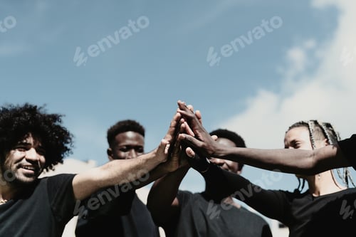 Preview: Happy group of African people having fun stacking hands together outdoor