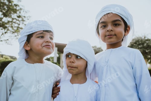 Preview: Children playing together in Dubai in the park. Group of kids wearing traditional kandura white