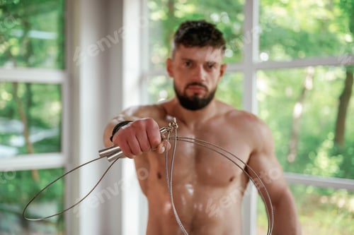 Preview: Holding jump rope. Strong muscular man is working out in the gym