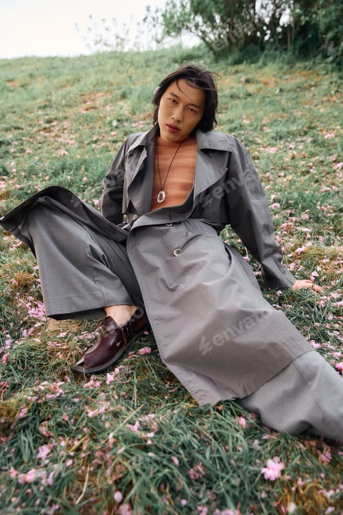 Preview: Stylish young man embraces nature in a chic grey outfit surrounded by blossoms