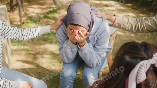 Preview: Muslim woman in trouble sharing story to diverse people sitting in circle at group therapy.