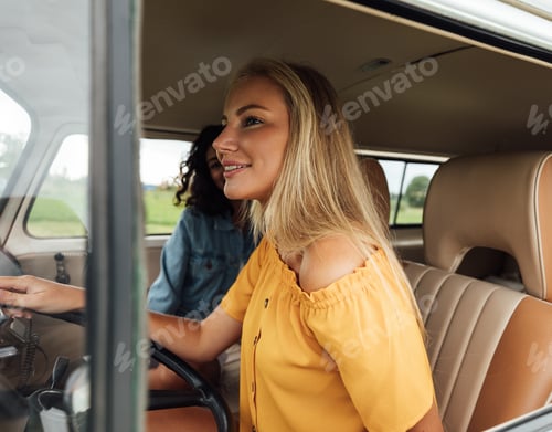 Preview: Blond woman driving a car. Two female friends sitting in a van during summer vacation.