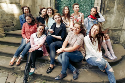 Preview: stylish happy girls hugging and smiling, having fun and relaxing in city street
