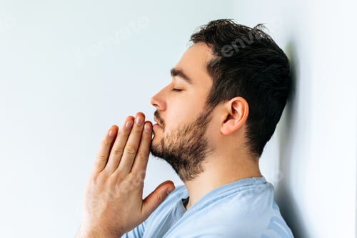 Preview: side view of a bearded man going through difficult period in life, praying.