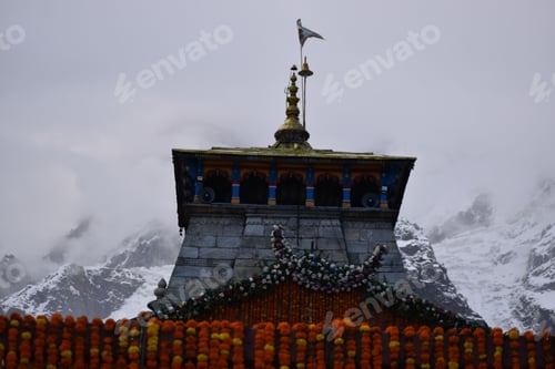 Preview: Low angle of the Kedarnath Temple decorated with marigold flower curtains in foggy weather