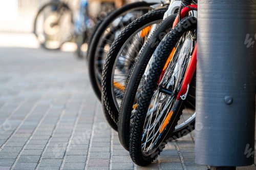 Preview: row of front wheels of bicycles in a bicycle rack, selective focus, close-up