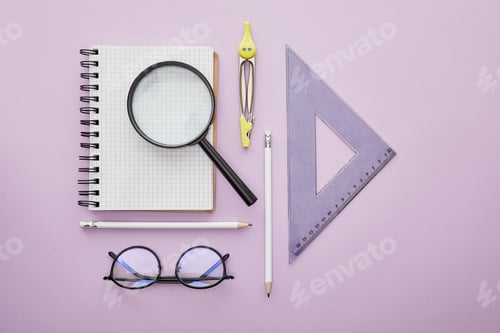 Preview: top view of ruler triangle near magnifier on notebook near pencils, drawing compass and glasses