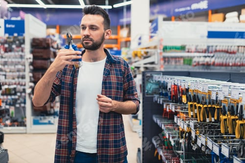 Preview: a male customer in a hardware store in the tool department chooses wire cutters