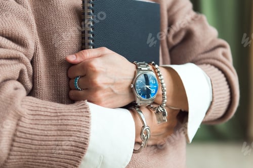Preview: fashion details - watches and bracelets on the hand of a business woman holding planner