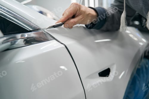 Preview: Skilled worker removing extra PPF coating from vehicle