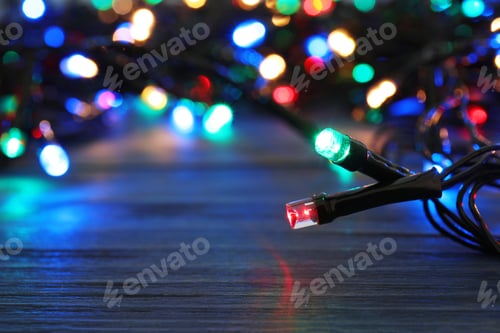 Preview: Glowing Christmas lights on wooden table, closeup