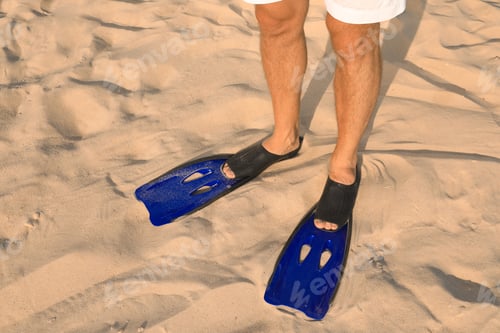 Preview: Man in blue flippers on sand, closeup view