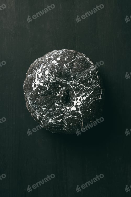 Preview: top view of black pumpkin with white paint splatters on dark halloween background