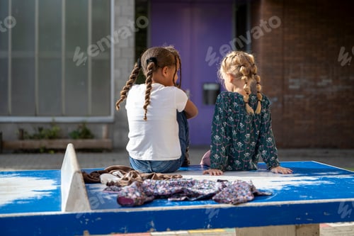 Preview: Two young friends sharing a moment on a sunny playground