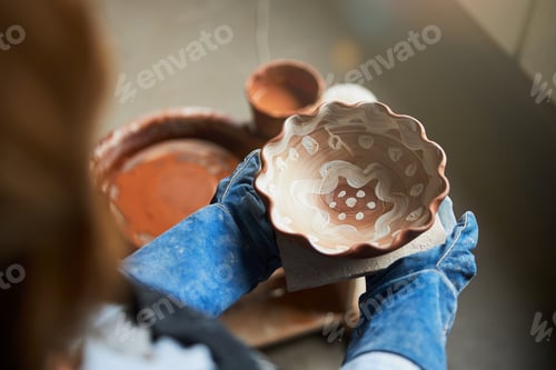 Preview: Female ceramic artist hands holding handmade earthenware bowl