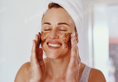 Preview: Cropped shot of an attractive young woman smiling while applying a coffee mask on her face at home