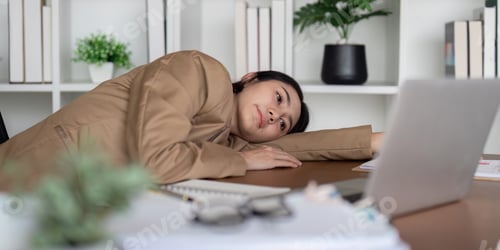 Preview: Frustrated businesswoman leaning on desk with laptop, feeling overwhelmed during a work session