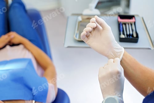 Vista previa: Close up of dentist prepairing for examination of patient, giving surgical gloves.