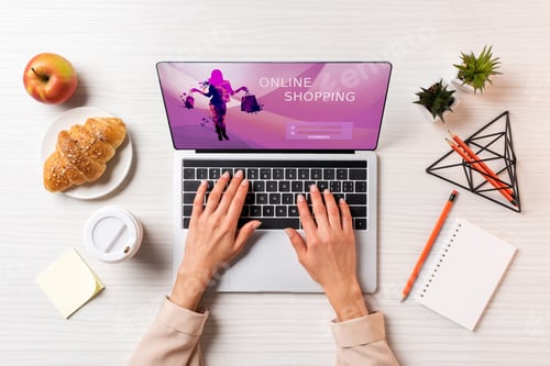Preview: cropped shot of businesswoman using laptop with online shopping website at table with coffee, apple