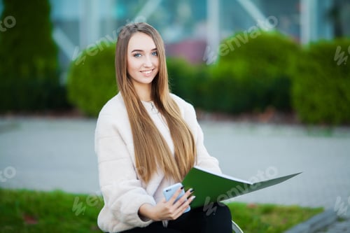 Preview: Smiling Young Woman Working Outdoors With Documents