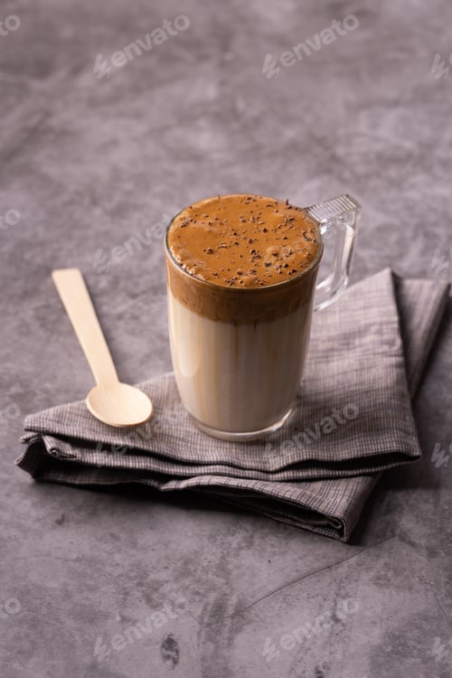 Preview: A glass of creamy dalgona coffee sprinkled with chocolate with napkin and wooden spoon