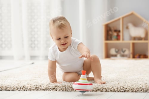Preview: Children toys. Cute little boy playing with spinning top on rug at home
