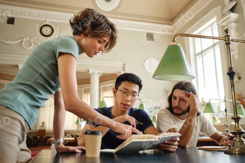 Preview: Young tutor helping thoughtful multinational students with study during lesson in university library