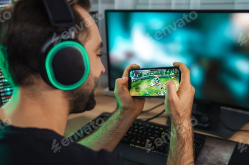 Preview: Young man gamer playing video games on smartphone
